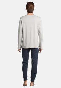 Graues Langarmoberteil aus weichem Stoff, kombiniert mit navyfarbenen Hosen mit elastischen Bündchen. Lässige Passform, klare Linien und minimalistische Details.