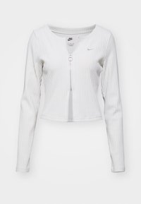 White ribbed long-sleeve top with a round neckline, front zipper closure with circular pull, and a small logo on the chest.