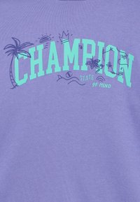 Μωβ βαμβακερό φούτερ με τη λέξη «CHAMPION» σε έντονα τιρκουάζ γράμματα, διακοσμημένο με γραφικά που απεικονίζουν φοίνικα, ήλιο και κύμα.