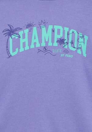 Lila pamut pulóver, amelyen „CHAMPION” felirat látható vastag türkiz betűkkel, díszítő pálmafás, napos és hullámos grafikákkal.