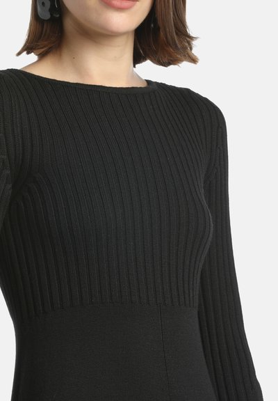 Fekete bordás kötött ruha, amely illeszkedő felsőrészével és hosszú ujjaival sima textúrával és finom fényességgel rendelkezik.