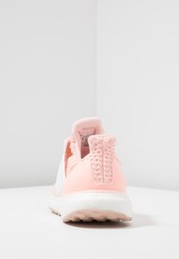 Damski but do biegania z fakturowaną, jasnoróżową cholewką z dzianiny, białymi akcentami i masywną białą podeszwą środkową z technologią boost.