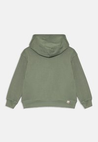 Hoodie vert avec une texture douce, poche kangourou, poignets et ourlet côtelés. Il dispose d'une capuche à l'arrière et d'une petite étiquette avec logo en bas.