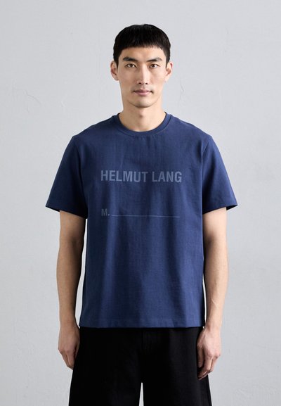 T-shirt en coton bleu marine avec le texte "HELMUT LANG" en gris, col rond, manches courtes et coupe décontractée. Texture lisse, design minimaliste.