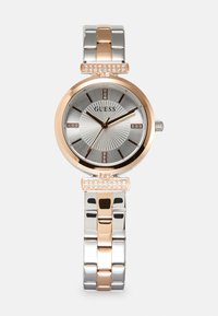 Montre en argent et or rose avec un cadran rond et cannelé, des accents en cristal et un bracelet en métal bicolore comprenant des maillons en argent et en or rose.