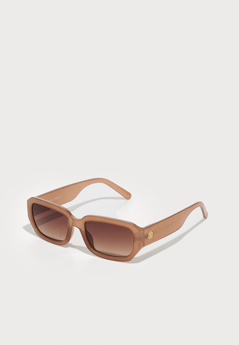 Gafas de sol rectangulares marrones con lentes en degradé, montura gruesa y un detalle de logo en el lateral. Material de plástico suave, diseño minimalista.