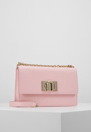 Sac à main en cuir rose clair avec une bandoulière en chaîne dorée et une boucle rectangulaire dorée sur le devant, posé sur une surface blanche.