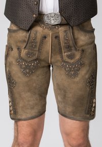 Hnědé kožené lederhosen s propracovanou černou výšivkou a dekorativními knoflíkovými detaily na straně, s jemnou texturou.
