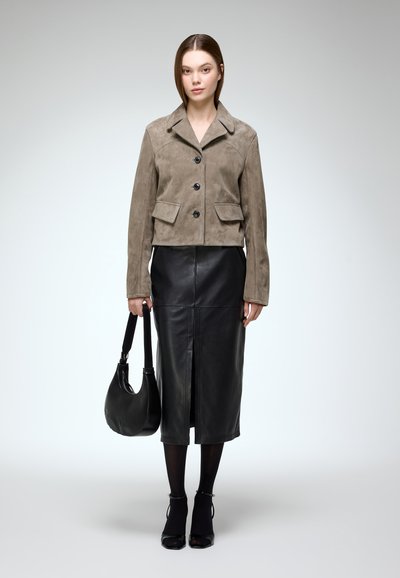 Brown suede cropped jacket with two front pockets, black buttons; paired with a black leather midi skirt and a curved black handbag.
