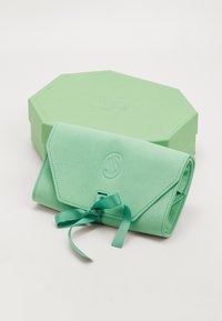 Mintgroene vegan leren clutch met een flap en lintsluiting, met reliëflogo detail en een bijpassende octagonale doos.
