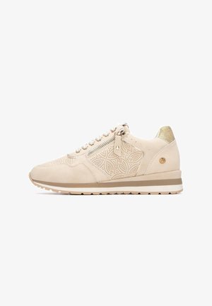 Zapatilla deportiva beige con diseño perforado, ante suave, detalles metálicos y un talón dorado texturizado. Cuenta con cierre lateral de cremallera y cordones.