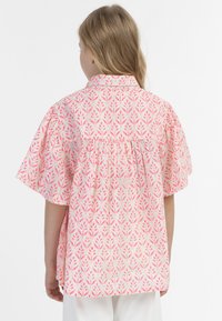 Camicia a maniche corte con motivo floreale rosa e bianco, dotata di pieghe sul retro e un design del colletto morbido, realizzata in tessuto leggero.