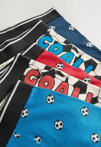 Fyra par kalsonger i olika färger: svart, blå, röd och vit. Mönster inkluderar fotbollar och ordet "MÅL" i fetstil.