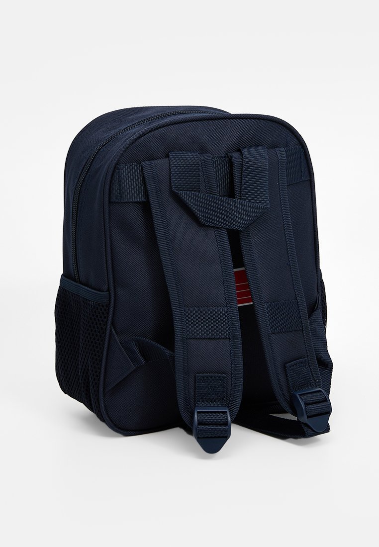 Zaino blu navy con due spalline regolabili, chiusura a zip e una tasca laterale in rete. Realizzato in tessuto resistente con una texture solida.