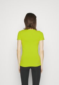 Camiseta ajustada de manga corta en un brillante verde lima, con detalles de costura en la parte posterior y un pequeño logo en el dobladillo. Textura suave.