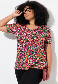 Tričko s krátkým rukávem a V výstřihem v živých květinových vzorech s růžovými, zelenými a oranžovými barvami na černém pozadí. Měkká tkanina s uvolněným střihem.