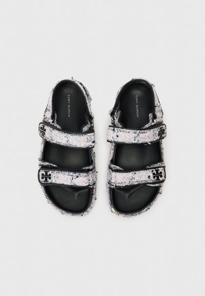 Fekete-fehér szandálok, két állítható tépőzárral, texturált felső rész foltos mintázattal, és sima fekete talppal.