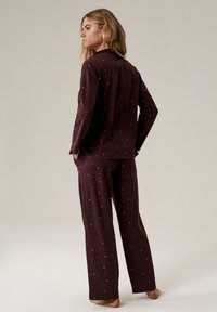 Ciemnoczerwony zestaw piżamowy z długimi rękawami i spodniami, zdobiony subtelnym wzorem księżyców i kropek, wykonany z miękkiego materiału dla zapewnienia komfortu.