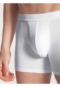 Boxer briefs bianchi in cotone con un elastico aderente e una tasca frontale. Presentano una texture liscia e un design aderente, mettendo in risalto uno stile pulito e minimal.