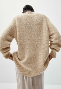 Beige knitted sweater with a relaxed fit, ribbed cuffs and hem, textured fabric, and a wide crew neckline.