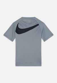 Hallide halli sportlik T-särk lühikeste varrukatega, millel on seljal must Nike'i logo, valmistatud tekstuurilisest, hingavast materjalist.