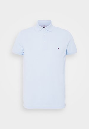 Jasnoniebieska koszulka polo z krótkim rękawem, kołnierzem, dwoma guzikami oraz małym logo Tommy Hilfiger na lewej piersi.