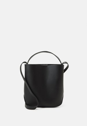 Schwarze Leder-Bucket-Bag mit einem oberen Griff und langem, verstellbarem Schulterriemen auf einfachem Hintergrund.