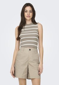 Pantaloni corti beige abbinati a una canotta attillata a coste di color marrone chiaro con strisce orizzontali bianche. Entrambi i capi sono casual e leggeri.