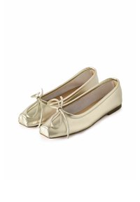 Bailarinas de cuero dorado con punta redonda, un pequeño lazo en la parte delantera y suela plana. Textura suave y diseño minimalista.
