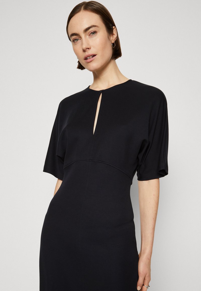 Kurzes ärahmiges Kleid in Marineblau aus weichem Material, mit einem Schlüssel-Ausschnitt, taillierter Passform und glatter Textur, die eine schlanke Silhouette betont.