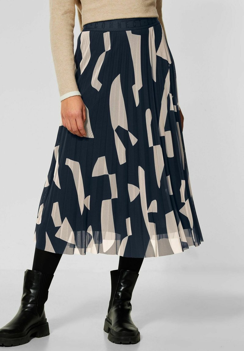 Gonna midi plissettata in navy con forme astratte beige. Realizzata in tessuto leggero, presenta una vita aderente e una finitura testurizzata.