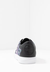 Sneaker in pelle nera con una parte superiore in paillettes colorate e testurizzate. Presenta una suola bianca e un emblema circolare del logo sul tallone.
