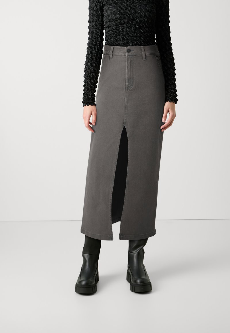 Grå denim maxi-skirt med en frontal split, høy midje og subtile sømdetaljer, kombinert med svarte plattform ankelboots.