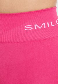 Fuchsia roze legging met een brede ribbelband met de tekst "SMILO" in het wit. Een gladde textuur en nauwsluitend ontwerp.