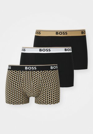 Trzy pary bokserek: jedna czarna z białym elastycznym paskiem, jedna czarna ze złotym elastycznym paskiem, oraz jedna w czarne i złote kółka.