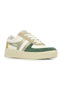 Scarpe da ginnastica con una tomaia in pelle bianca, dettagli beige e dorati, punta in suede verde e tallone giallo. La suola è texturizzata e di colore crema.