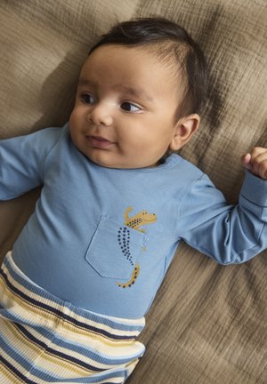 Blå skjorta med långa ärmar och en ficka med en gul ödlebild, kombinerad med randiga underdelar i färgerna gräddvit, blå och gul. Texturerat tyg.