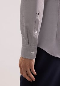 Camicia a maniche corte con motivo pied de poule in bianco e nero, dettaglio polsino con bottoni e tessuto liscio.