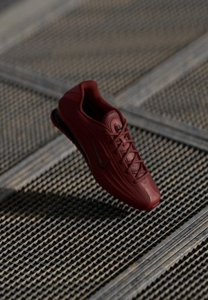 Roter Sportschuh mit strukturiertem Obermaterial, Schnürsenkeln und Nike-Logo. Entwickelt für Leistung mit einer schlanken Silhouette und unterstützender Struktur.