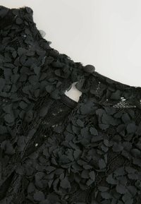 Zwarte kantstof met textuur bloemen appliqués, met een ronde halslijn en knoopsluiting aan de achterkant. Gedetailleerd en ingewikkeld ontwerp.