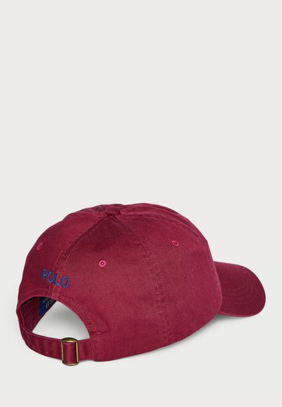 Maroon cap with a curved brim, textured cotton fabric, and blue "POLO" embroidery at the back. Adjustable strap with metal buckle.