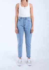 Ljusblå högmidjade jeans med rak skärning, tillverkade av denim. Har fem fickor och bälteshällor, kombinerat med vita sneakers.