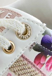 Sneaker in pelle bianca con stampa floreale e dettagli rosa e viola. Fori per i lacci con finiture dorate e cuciture dorate testurizzate.