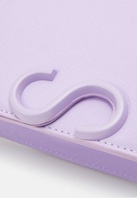 Violetti tekstuuri kangas, jossa kiiltävä lilanvärinen S-muotoinen koukku on merkittävä piirre. Muotoilu on yksinkertainen ja moderni.