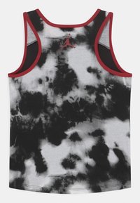 Czarnobiały top na ramiączkach w stylu tie-dye z czerwonymi wykończeniami. Posiada szerokie dziurki na ramiona i okrągły dekolt. Logo umieszczone na plecach w pobliżu kołnierza.