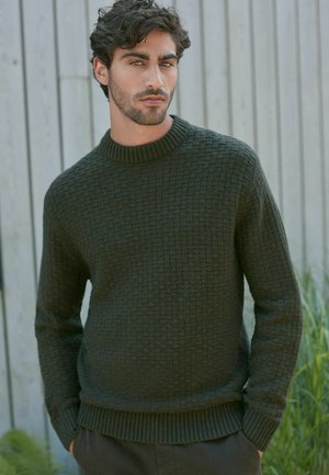 Pulover tricotat de culoare verde închis, cu un model texturat, guler rotund rib suportat și mansete, având o croială lejeră și un design de culoare uni.