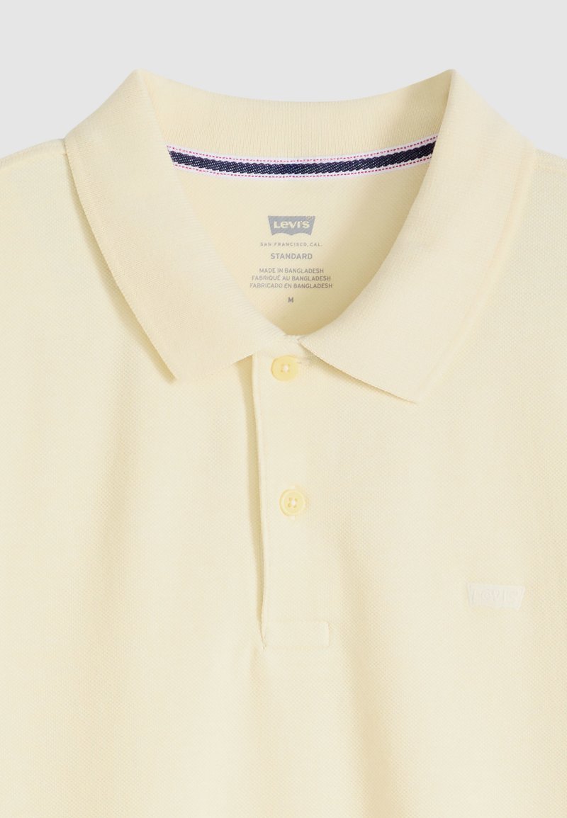 Polo Levi's jaune clair avec deux boutons, un col et un petit logo sur la poitrine gauche, taille moyenne, fabriqué au Bangladesh.