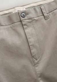Light gray fabric pants with a smooth texture. Features a button closure, belt loops, and a front pocket. Subtle stitching details.