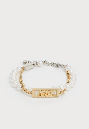 Bracelet doré mettant en vedette un charme rectangulaire avec "DS02", combiné avec des perles en nacre blanche et un élément de chaîne en or torsadé.