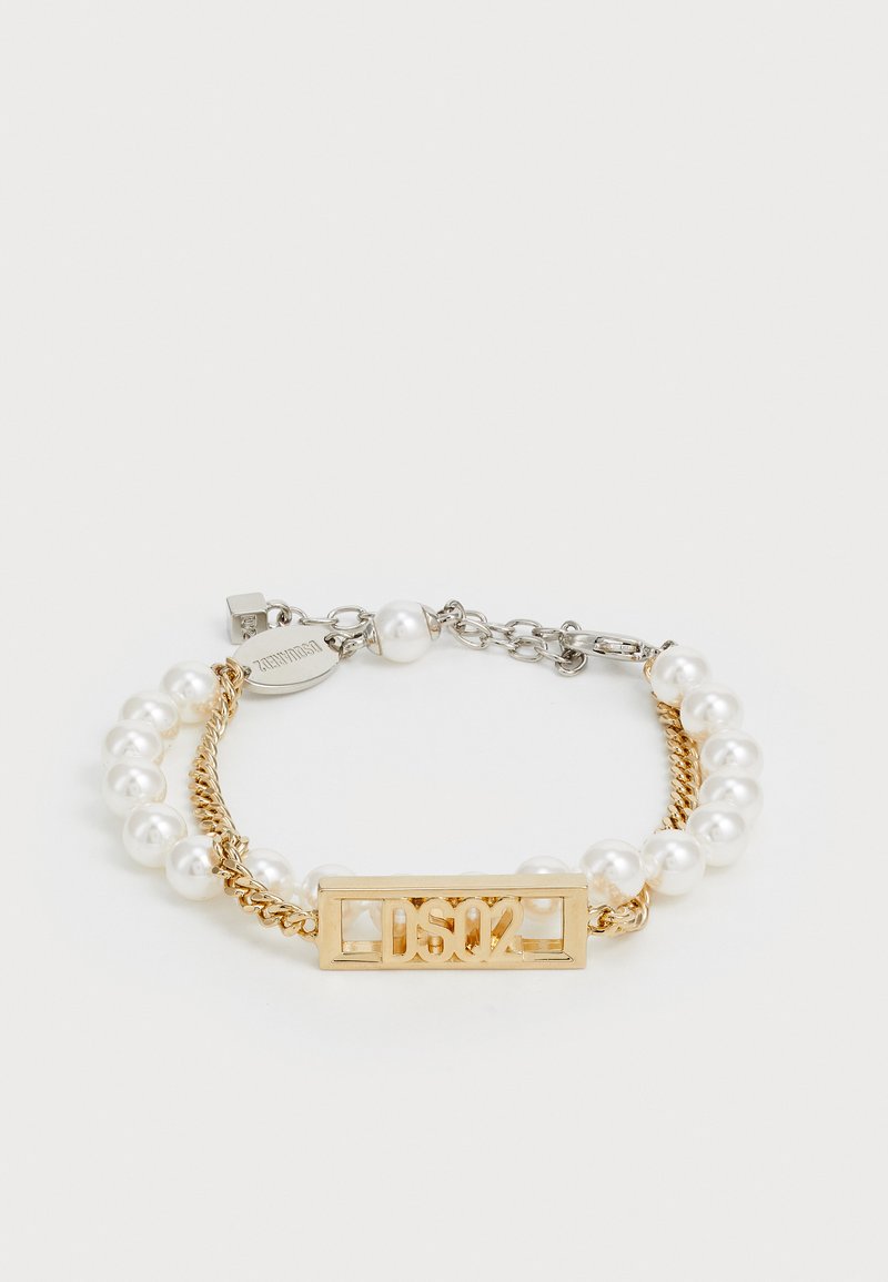 Aranyszínű karkötő, amelyen egy téglalap alakú charm található "DS02" felirattal, fehér gyöngyökkel és egy csavart aranylánc elemmel kombinálva.